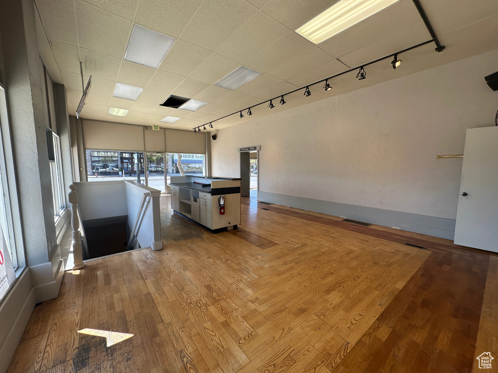 Interior space featuring track lighting, healthy amount of natural light, baseboards, wood finished floors, and a drop ceiling