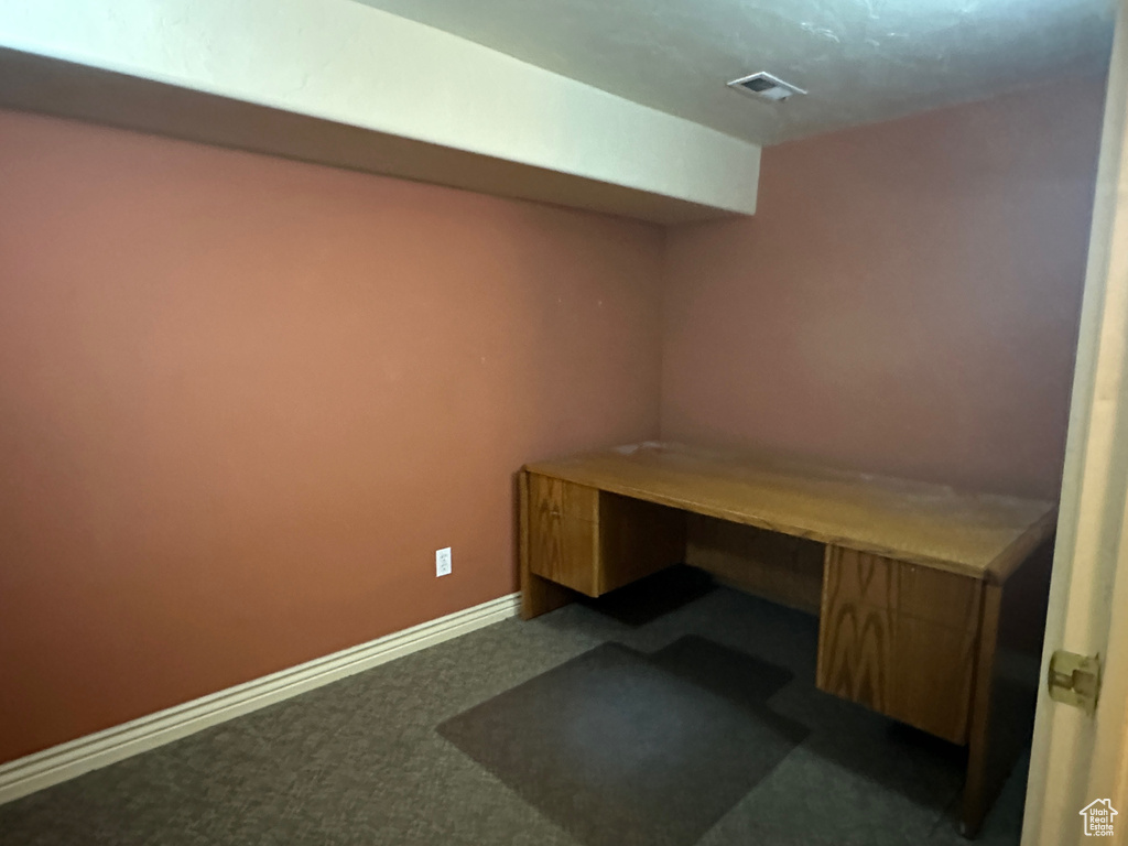 Unfurnished office featuring dark carpet and baseboards