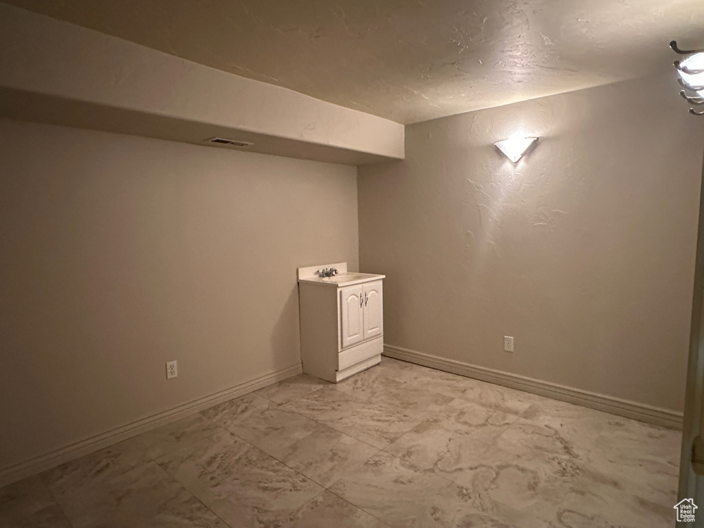 Finished below grade area with baseboards, light marble finish floors, and a textured ceiling