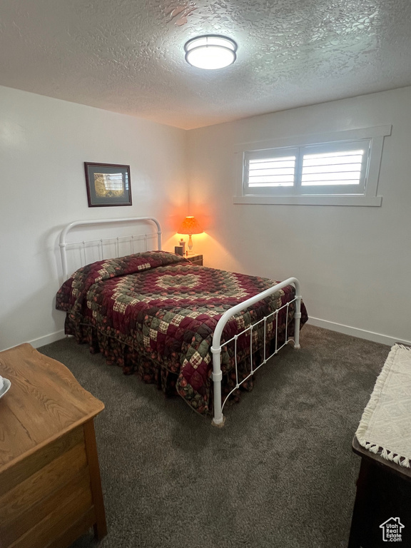 Bedroom with a textured ceiling, carpet, and baseboards