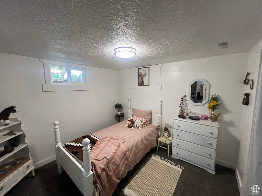 Bedroom featuring baseboards, a textured ceiling, and carpet