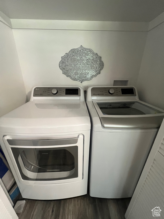 Clothes washing area with dark wood-style flooring and washing machine and dryer