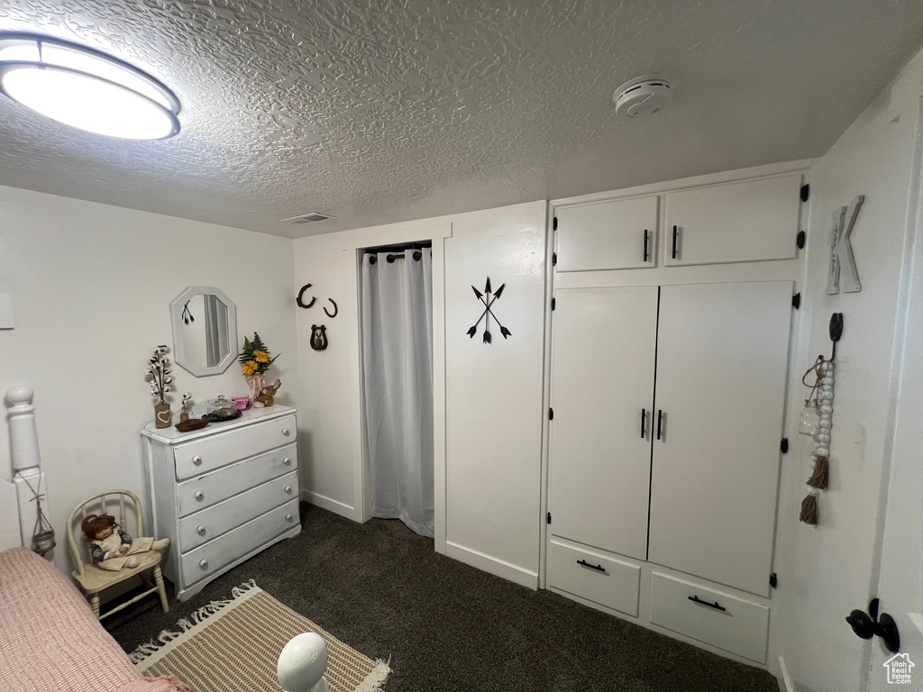Bedroom featuring a textured ceiling and dark colored carpet