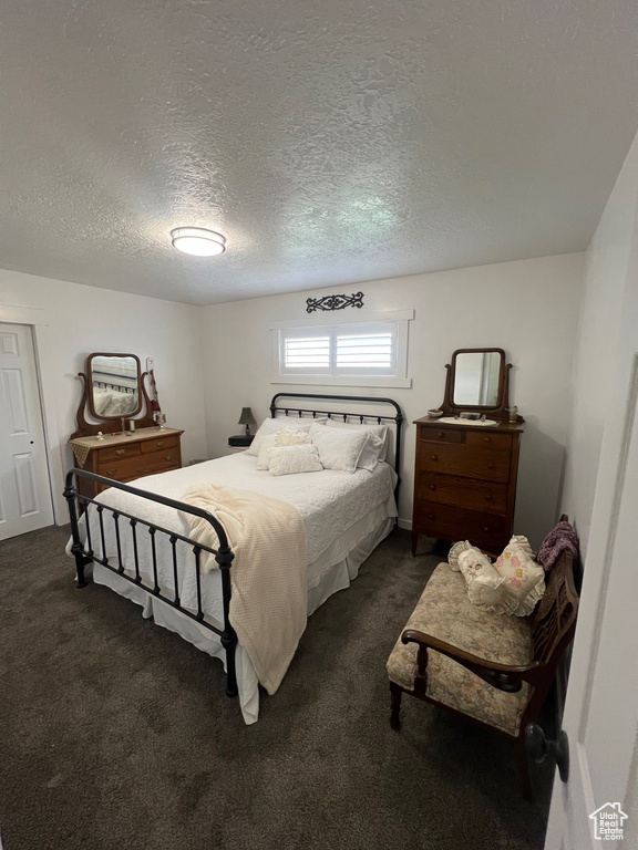 Bedroom with dark colored carpet and a textured ceiling