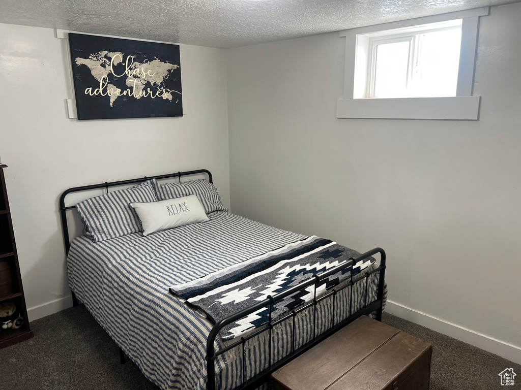 Carpeted bedroom with a textured ceiling and baseboards