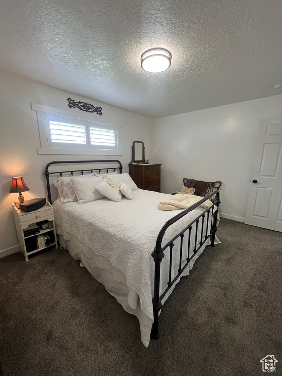 Bedroom with dark colored carpet, a textured ceiling, and baseboards