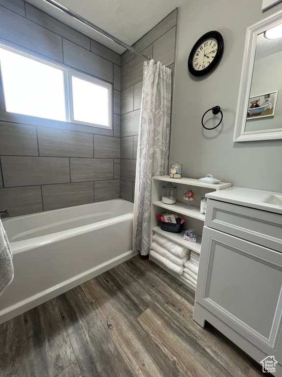 Full bathroom with wood finished floors, shower / tub combo with curtain, and vanity