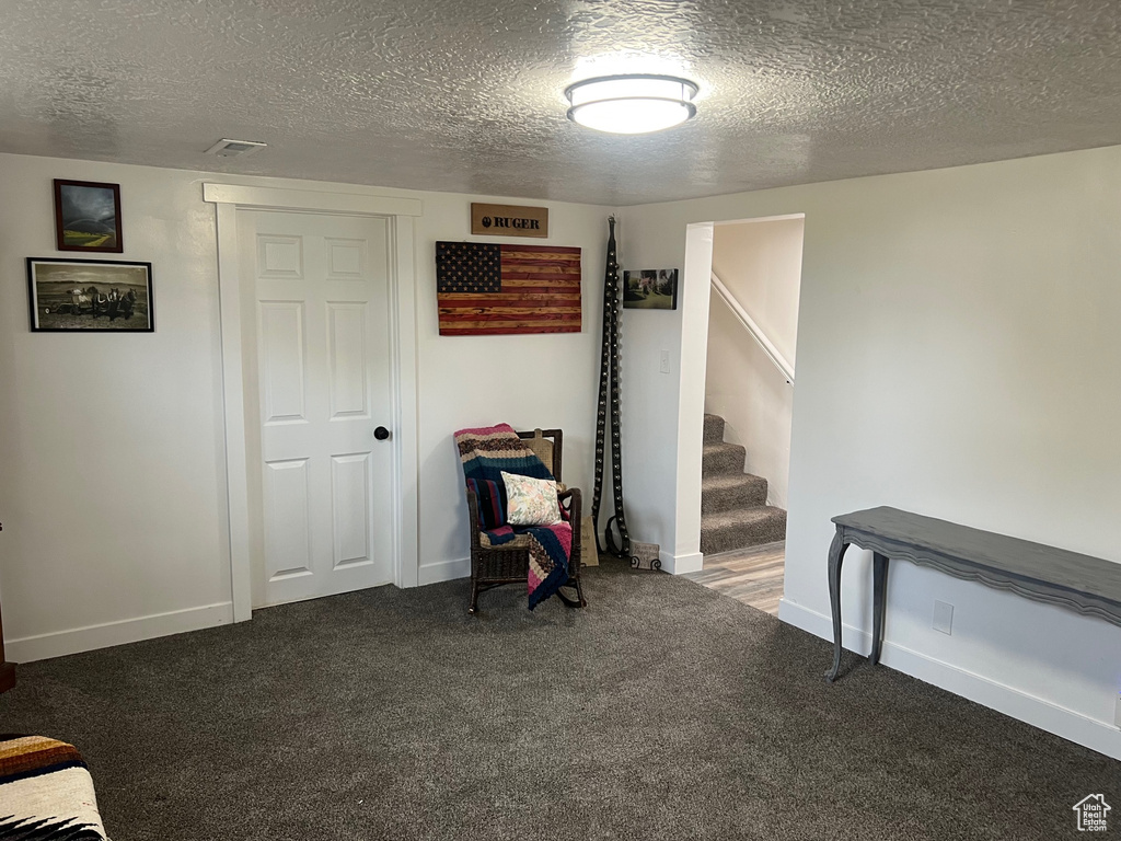 Finished basement featuring carpet floors, a textured ceiling, stairs, and baseboards