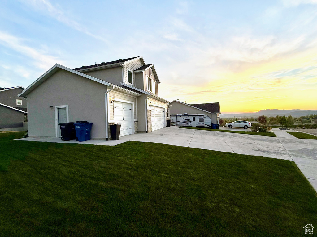 View of home\\\\\\\'s exterior featuring concrete driveway, a yard, a garage, and stucco siding