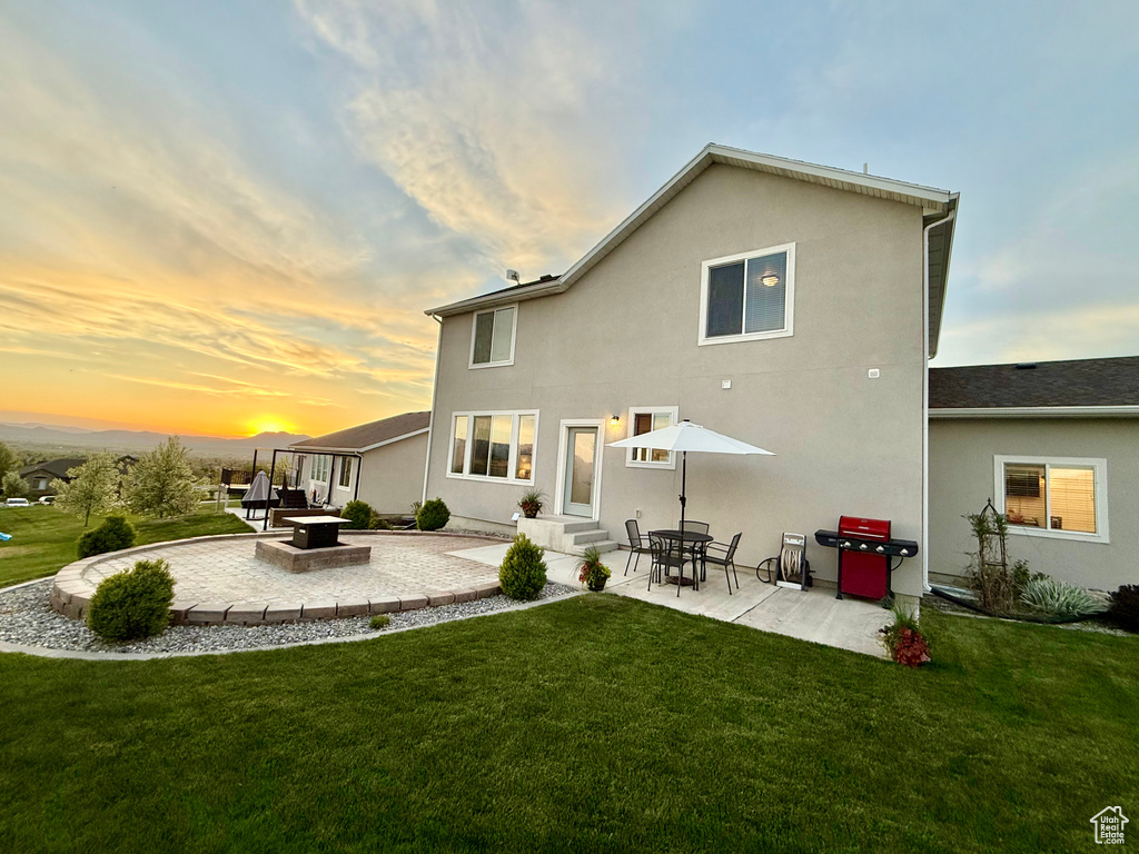 Back of property at dusk featuring a patio, a yard, entry steps, and stucco siding