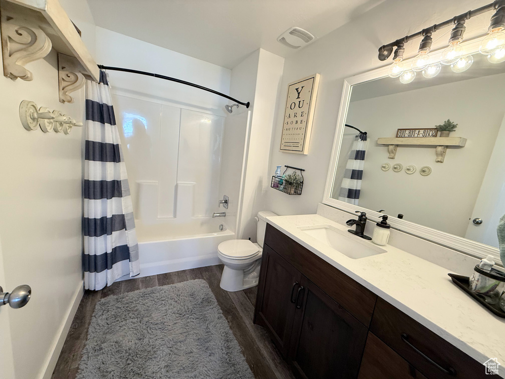 Bathroom featuring wood finished floors, vanity, toilet, and shower / bath combination with curtain