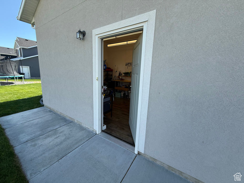 Entrance to property with a patio, a yard, and stucco siding