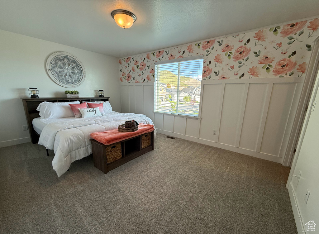 Carpeted bedroom with wallpapered walls, a wainscoted wall, and a decorative wall