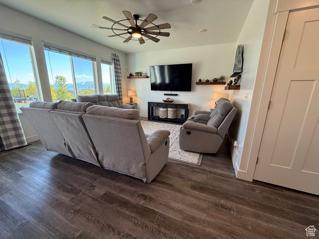 Living area featuring baseboards, dark wood-style flooring, and a ceiling fan