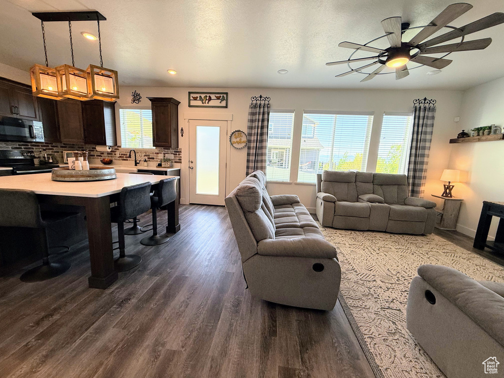 Living room with healthy amount of natural light, dark wood-type flooring, ceiling fan, recessed lighting, and baseboards