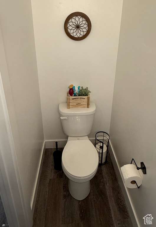 Bathroom with wood finished floors, toilet, and baseboards