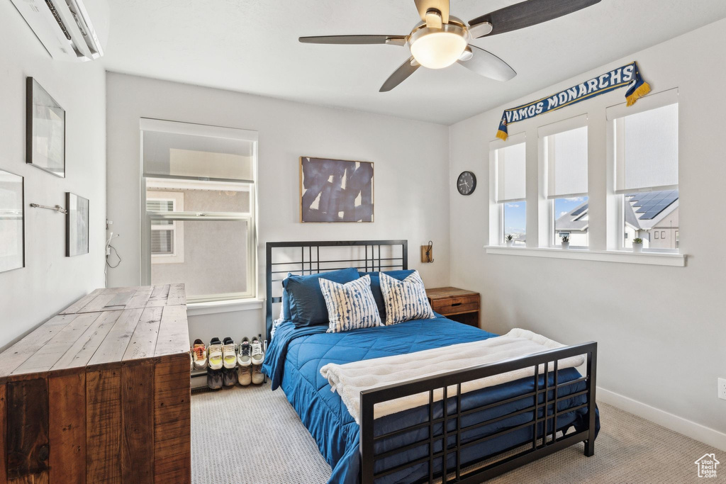Carpeted bedroom featuring a wall mounted air conditioner, baseboards, and a ceiling fan