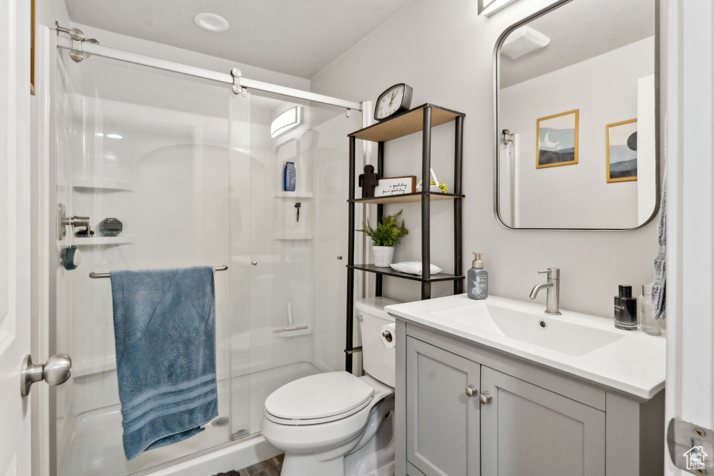 Bathroom with a stall shower, toilet, and vanity