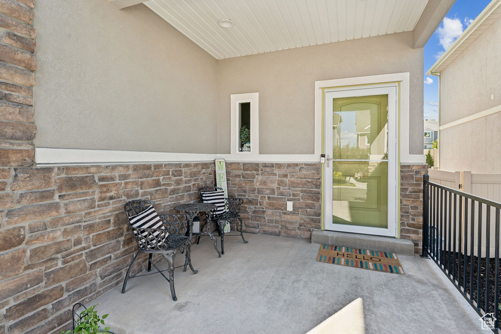 Doorway to property with stucco siding, stone siding, and a patio