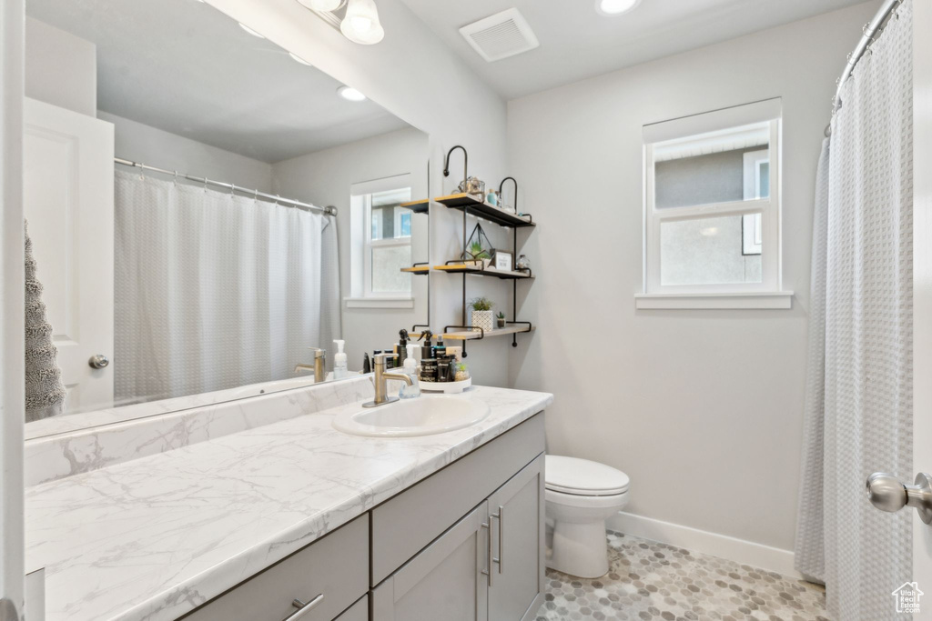 Bathroom with toilet, baseboards, vanity, and recessed lighting