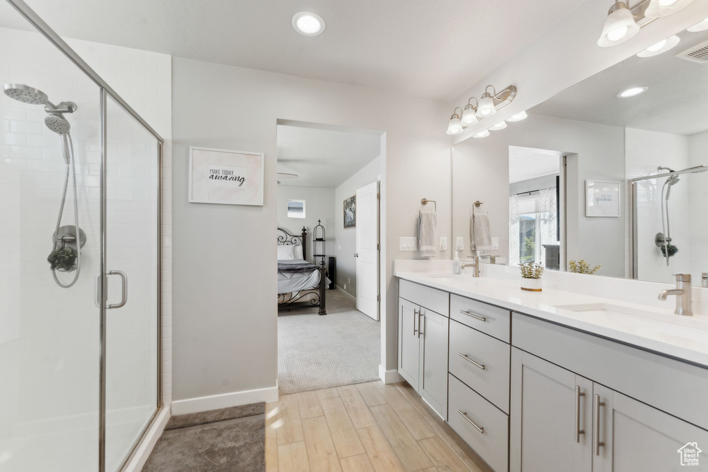 Full bath with a shower stall, double vanity, ensuite bathroom, wood finished floors, and baseboards
