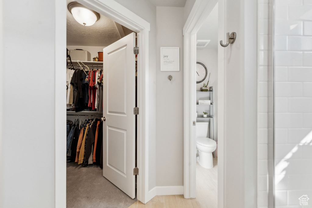 Bathroom with a spacious closet, toilet, and baseboards