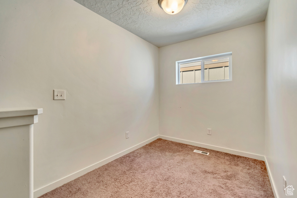 Unfurnished room featuring a textured ceiling, baseboards, and carpet