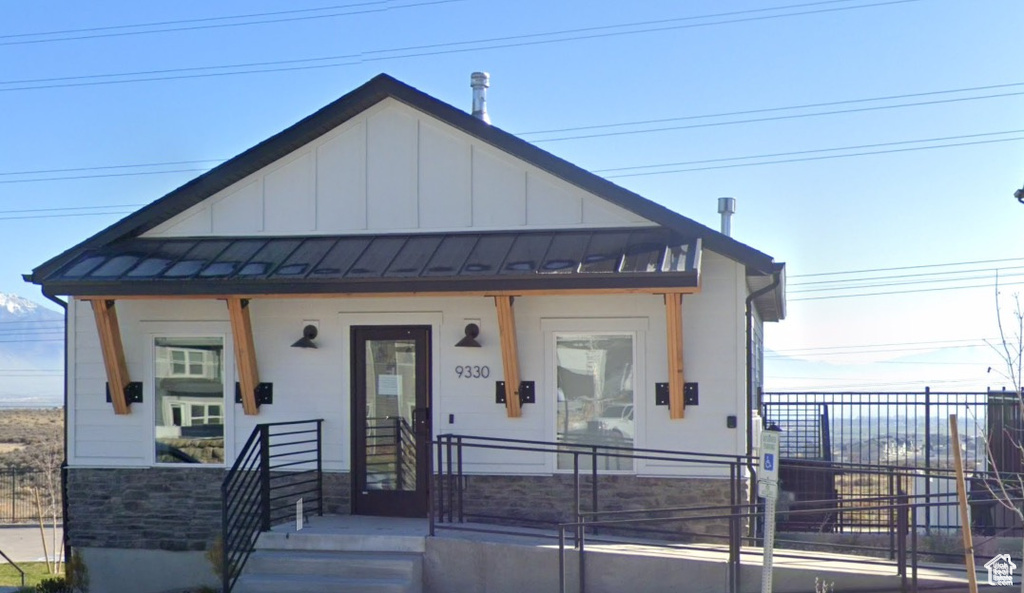 View of front of house featuring fence, a standing seam roof, a porch, board and batten siding, and stone siding