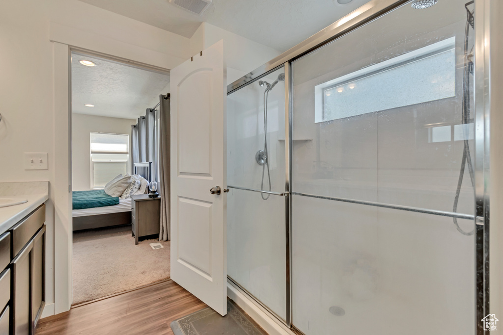 Full bathroom featuring wood finished floors, a stall shower, ensuite bath, and vanity