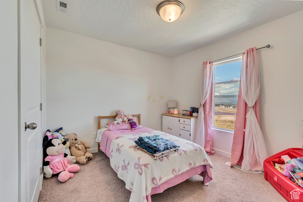 Bedroom with light colored carpet, baseboards, and a textured ceiling