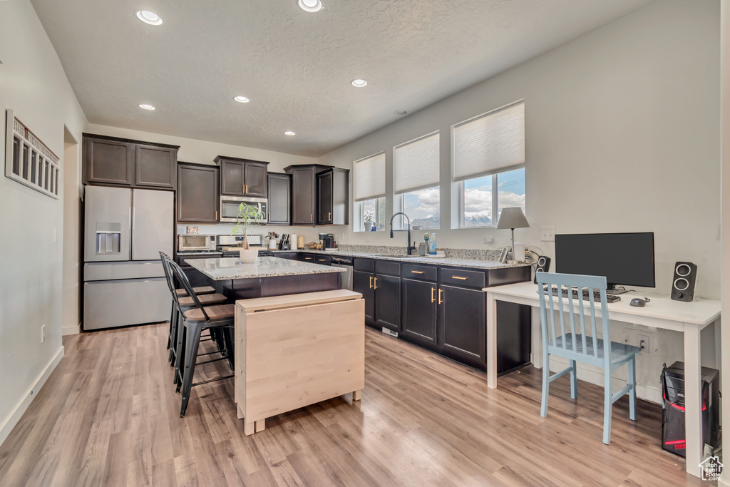 Kitchen featuring stainless steel appliances, a sink, a center island, recessed lighting, and light wood finished floors