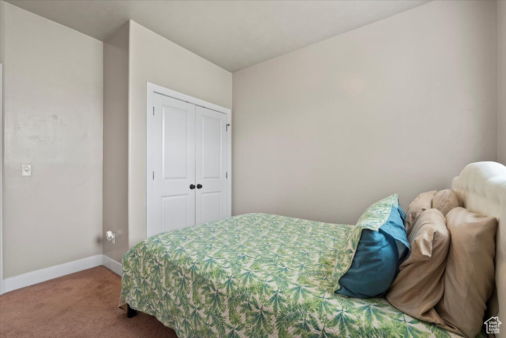 Bedroom with carpet flooring, a closet, and baseboards