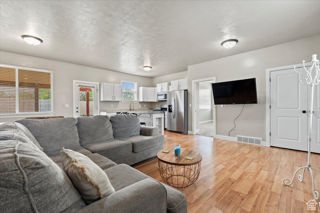 Living area with light wood finished floors, baseboards, and a textured ceiling