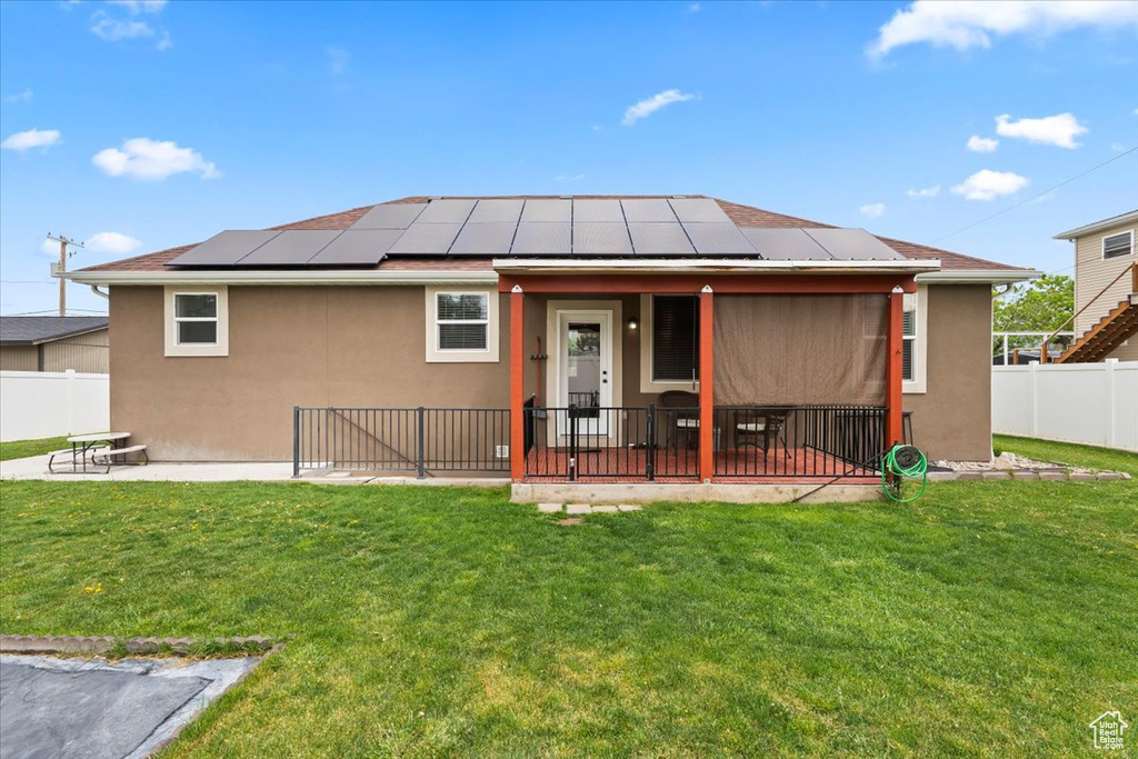 Back of house with solar panels, stucco siding, and a patio area