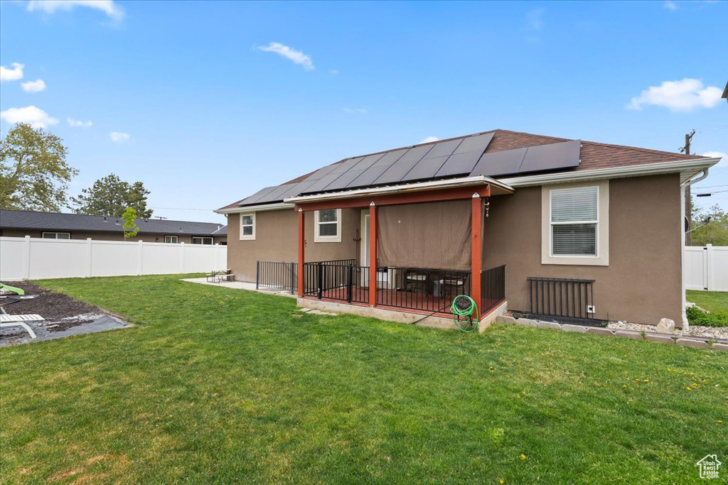 Rear view of house featuring solar panels, stucco siding, and a patio area