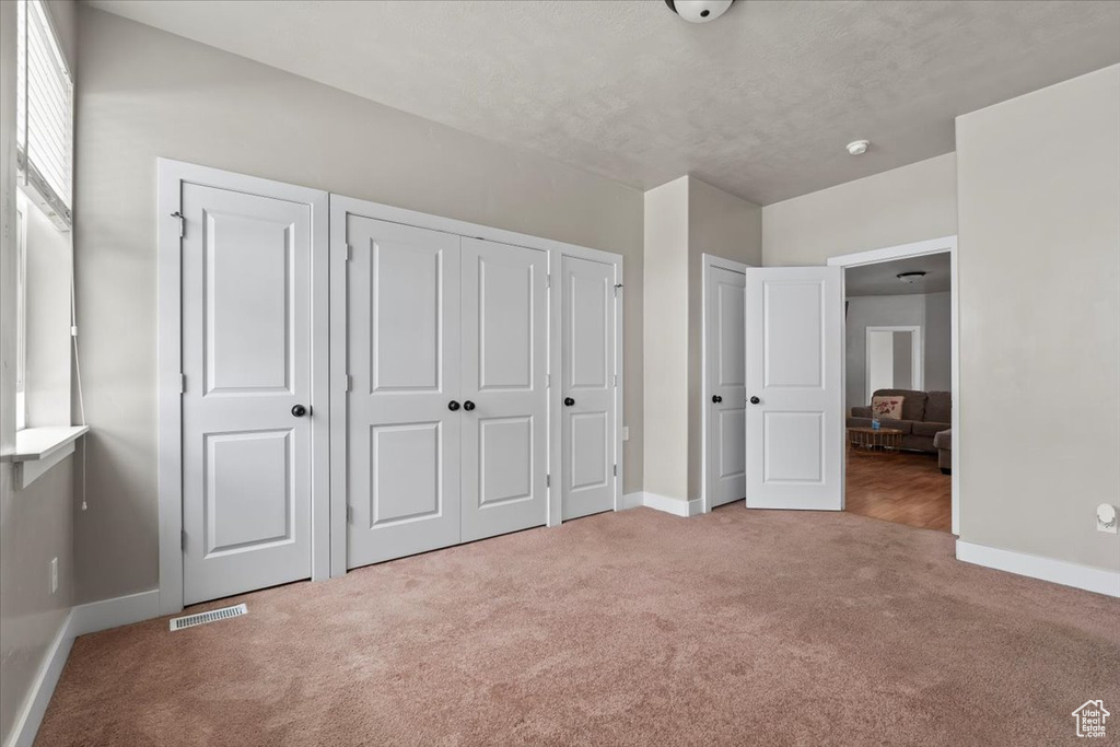 Unfurnished bedroom featuring carpet floors, baseboards, and a closet