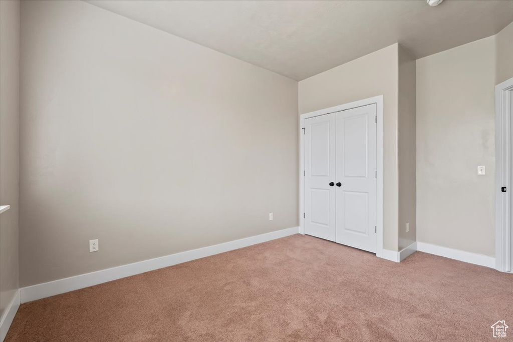 Unfurnished bedroom with light carpet, baseboards, and a closet