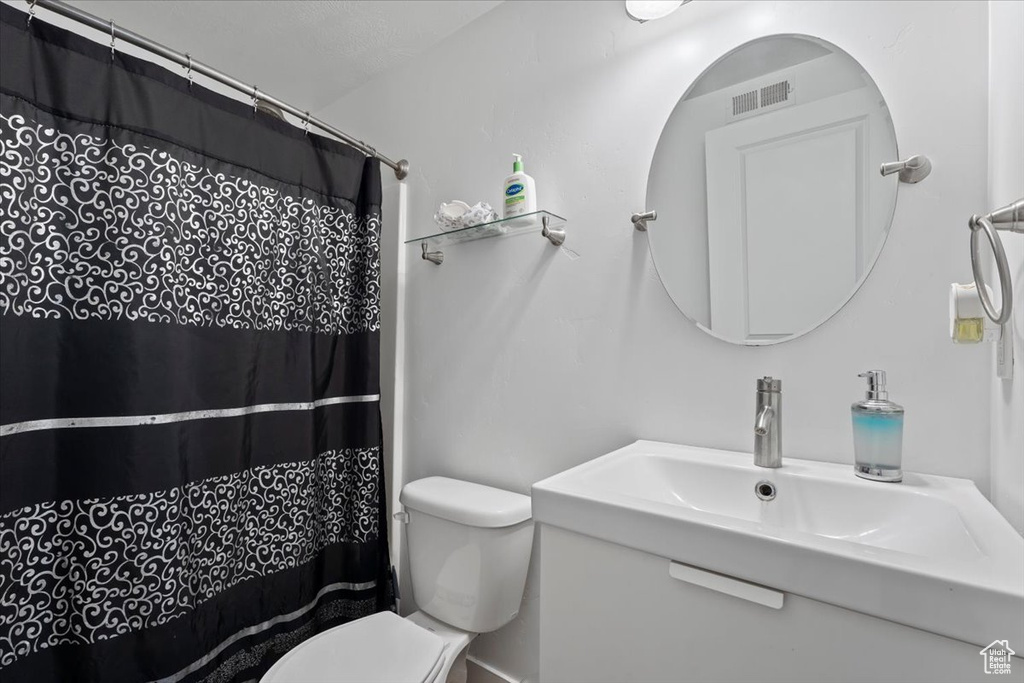 Bathroom with toilet, a sink, and a shower with shower curtain