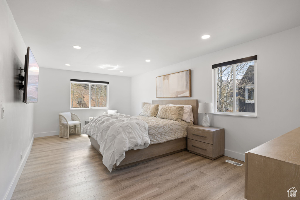 Bedroom featuring multiple windows, light wood-style floors, baseboards, and recessed lighting