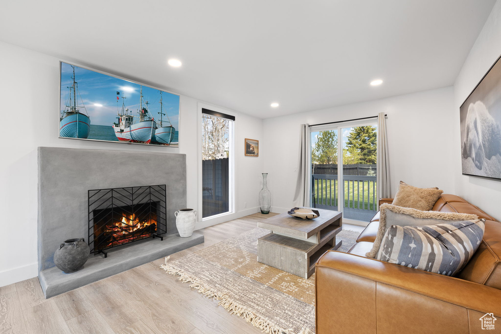 Living room featuring a warm lit fireplace, wood finished floors, recessed lighting, and baseboards