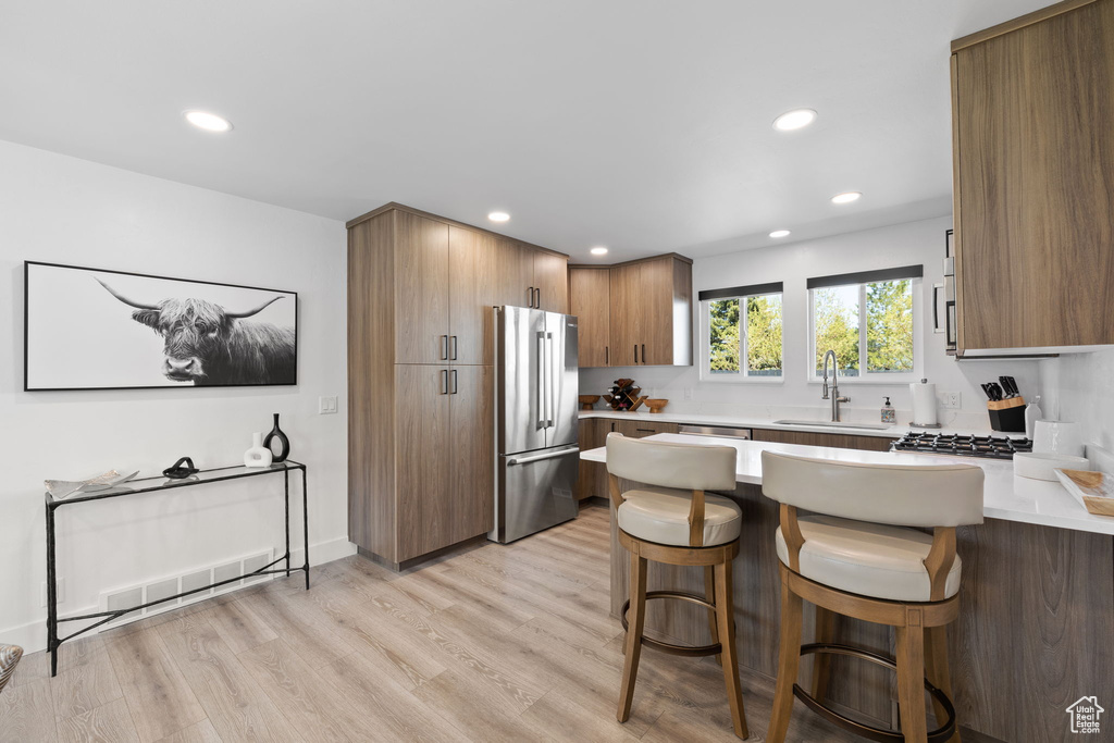 Kitchen featuring freestanding refrigerator, a peninsula, a sink, a kitchen breakfast bar, and recessed lighting