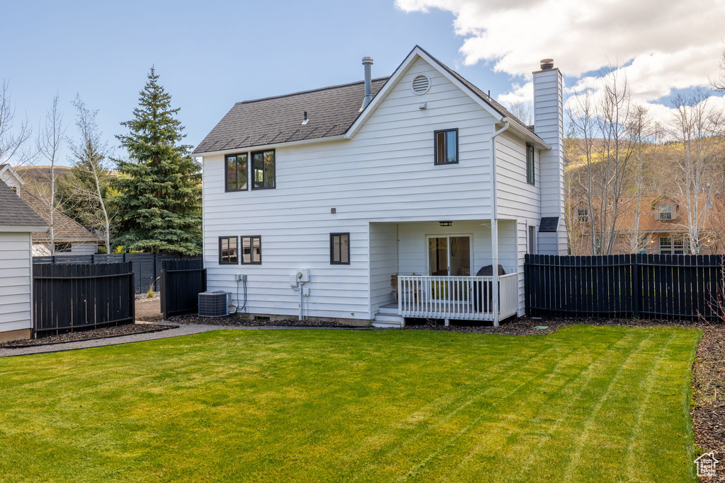 Rear view of property featuring central AC unit, a chimney, and a deck