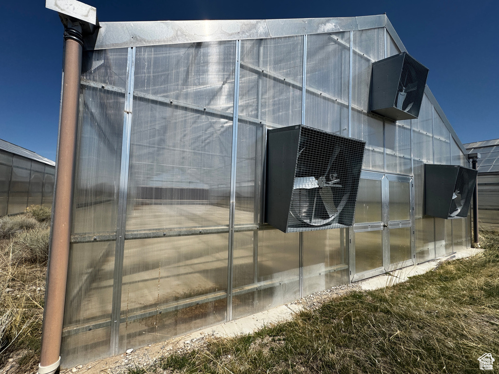 View of property exterior featuring a greenhouse and an outbuilding