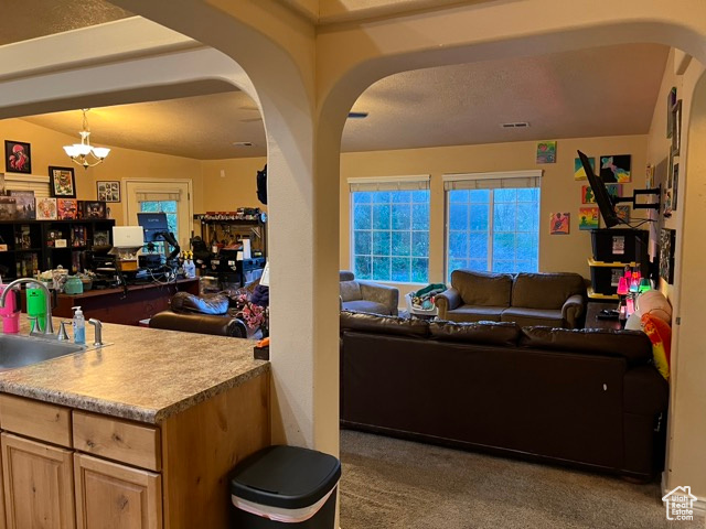 Living room with carpet floors, arched walkways, and a chandelier