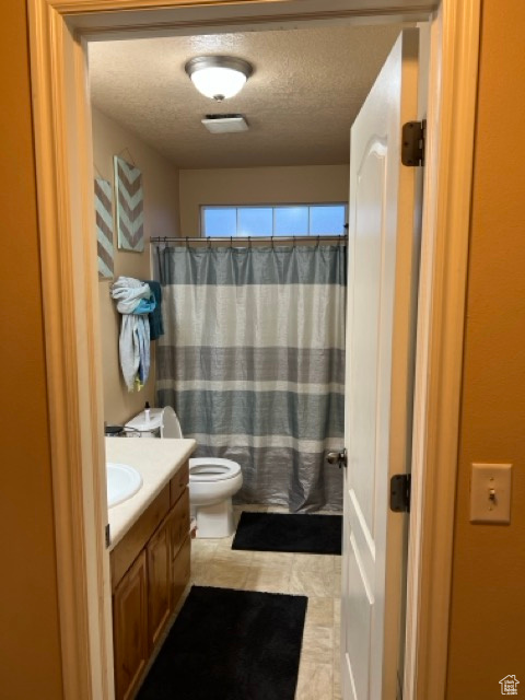 Full bathroom with vanity, a textured ceiling, toilet, a shower with curtain, and tile patterned flooring
