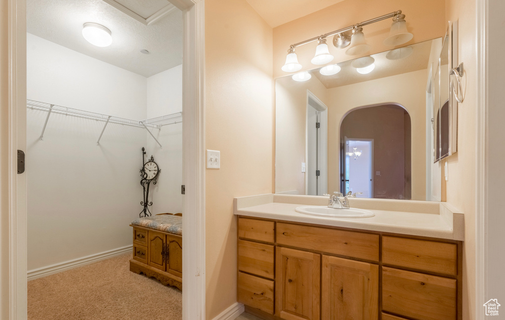 Bathroom featuring a walk in closet, vanity, and baseboards