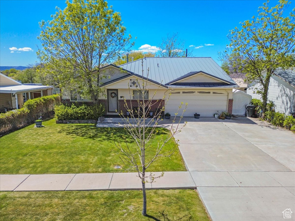 View of front of house featuring brick siding, a garage, concrete driveway, and a front lawn