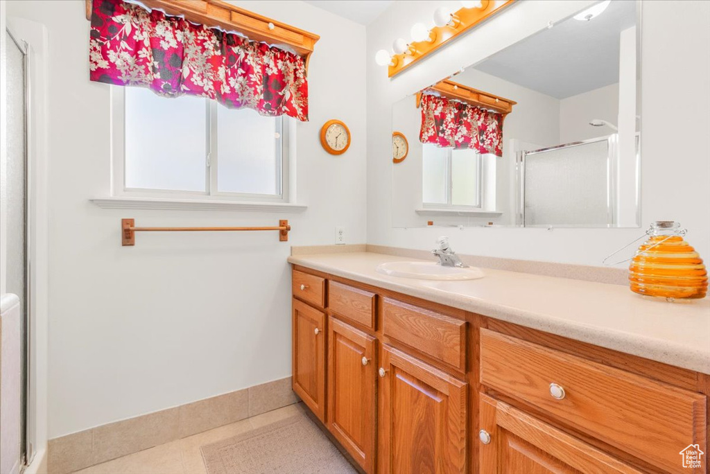 Bathroom with vanity, a shower with shower door, and baseboards