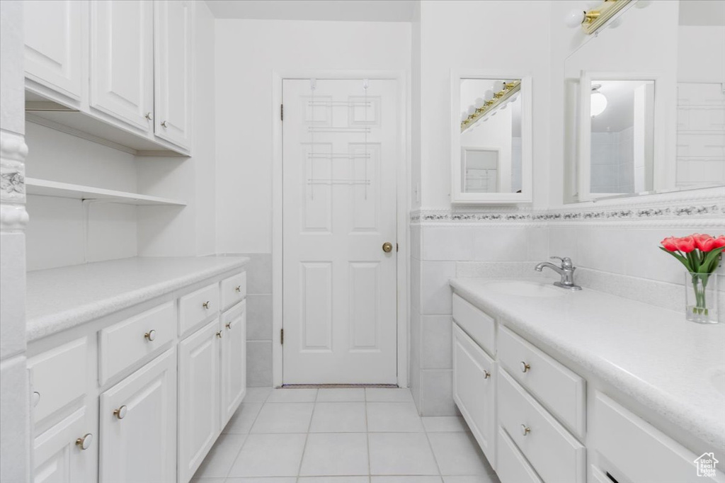 Bathroom with tile patterned floors, vanity, and tile walls
