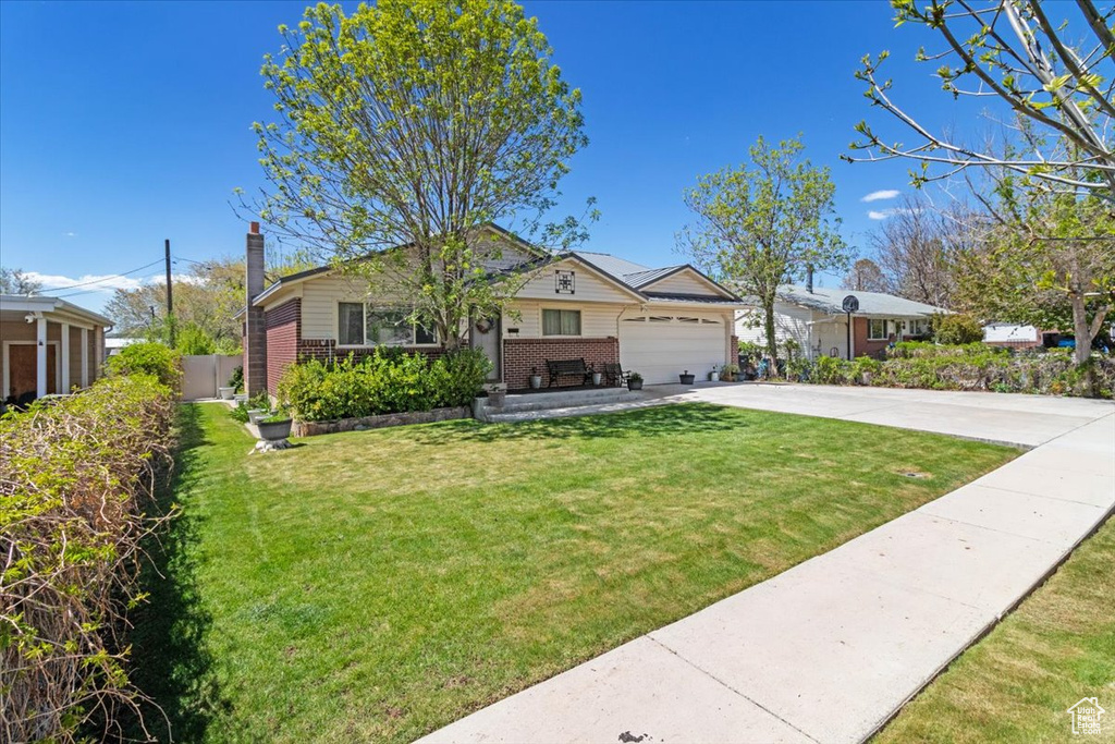 Bungalow with brick siding, driveway, an attached garage, and a chimney